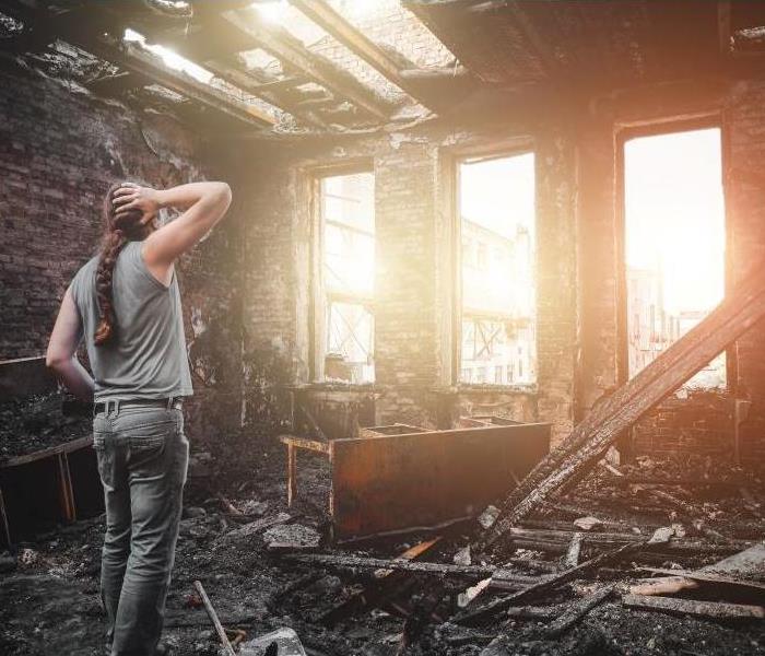 a person standing in a part of a house that is now completely destroyed after a fire